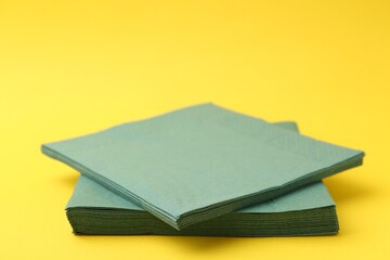 Stack of green handkerchiefs on yellow background, closeup. Space for text