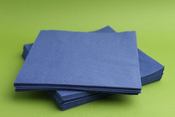 Stack of blue handkerchiefs on green background, closeup
