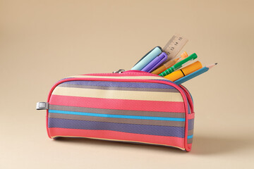 Different stationery in pencil case on beige background