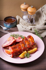 Roasted rack of pork ribs with apples on a plate and brown wood background