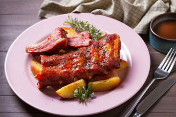 Roasted rack of pork ribs with apples on a plate and brown wood background