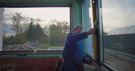 Worker using level tool to ensure window frame alignment at construction site, close-up of focused...