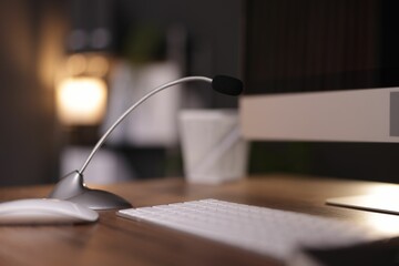 Microphone and computer on wooden desk indoors