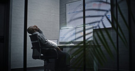 Financial Analyst Suffering from Financial Crisis, Yelling in Phone, Analyzing Real-Time Market Charts in Office at Night. African American Businessman Furious About Sudden Stock Market Collapse.
