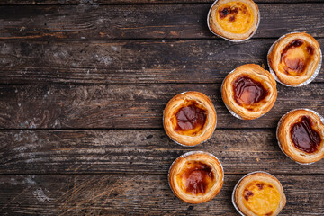 Traditional Portuguese custard tarts or Pastel de Nata freshly baked cream dessert on wooden background. Top view, flat lay. High quality photo
