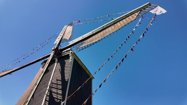 Heusden, Brabant, Netherlands - May 17th 2025: Dutch windmill with flags turning in the wind