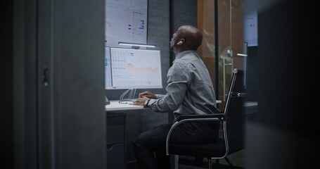 Financial Analyst Suffering from Financial Crisis, Yelling During Call, Analyzing Exchange Market Charts in Office at Night. African American Businessman Furious About Sudden Stock Market Collapse.
