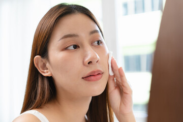 Close-up view woman using toner and cotton pad to remove makeup