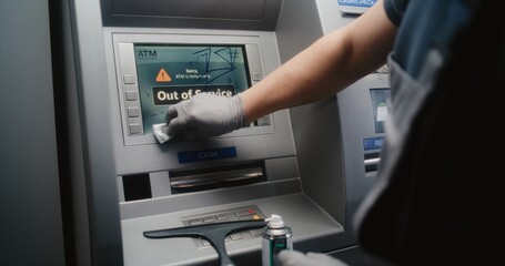 Cleaner Wiping Vandalized ATM Screen with Rag, Removing Graffiti, Scribbled Tags from Automated Teller Machine, Cash Machine. Cleaning Service, Property Damage, Vandalism of Public Banking Equipment.