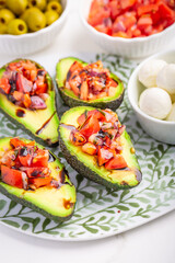 Vegan appetizers, avocados filled with bruschetta and balsamico vinaigrette