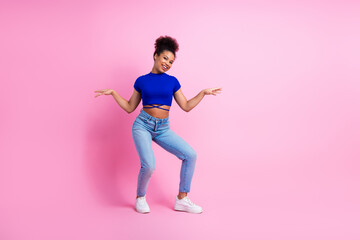 Happy young woman dancing cheerfully in stylish outfit against vibrant pink background showcasing joy and energy