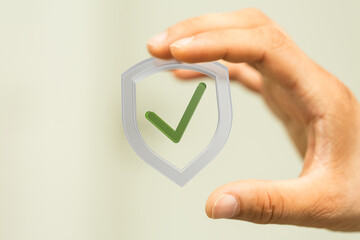 Image of a hand holding a digital shield with a check mark, symbolizing data security and...