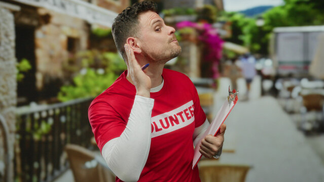 Volunteer man listens attentively holding clipboard in vibrant urban street setting featuring colorful backgrounds and casual atmosphere on a sunny day reflecting community spirit.