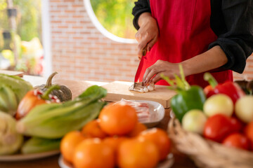 A woman is cutting vegetables on a cutting board