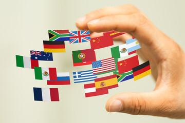 Image of a hand gently holding various national flags, symbolizing international collaboration and...