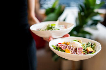 Two bowls of fresh, vibrant salads—one with seared tuna, mixed greens, and a poached egg, the other with assorted vegetables. Natural light enhances the appetizing presentation.