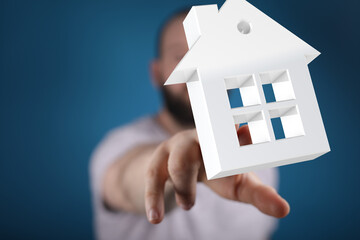 A man's hand reaches towards a white 3D house model. Perfect for real estate, home buying, and...