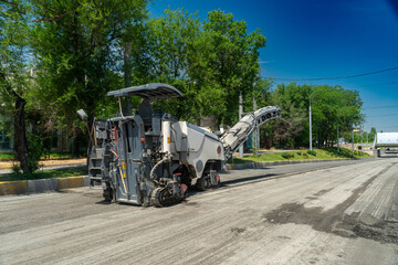 Heavy road milling equipment grinds and removes worn asphalt surface, preparing roadway for new...