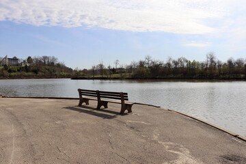 The empty wood bench on the shore at the lake.