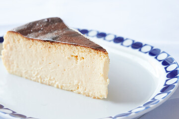 Slice of creamy Spanish cheesecake made with traditional Idiazabal cheese served on a dessert plate. Basque recipe.