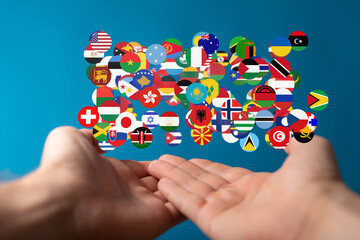 Image of hands gently holding a cluster of diverse national flags, symbolizing global unity and...