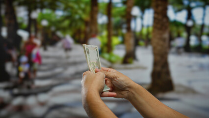 Man holding uae dirham banknotes on a busy urban street, showcasing currency handling in an outdoor business setting.