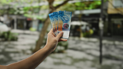 Man holding swiss franc banknotes in hand on a city street, showcasing vibrant currency outdoors against urban backdrop, highlighting financial concept in an open environment.