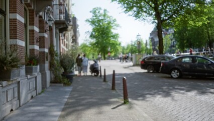 Bokeh view of european city street with people talking near parked cars on a sunny day, featuring blurred surroundings, trees, and urban architecture.