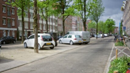 European street scene with blurred cars and buildings in the background, showcasing a defocused view of a calm urban neighborhood under cloudy skies.