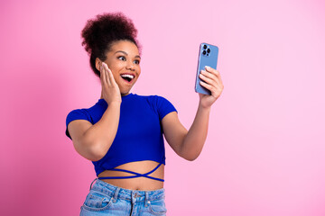 Excited girl holding smartphone expressing amazement with vibrant background and casual fashion emphasizing lively modern style