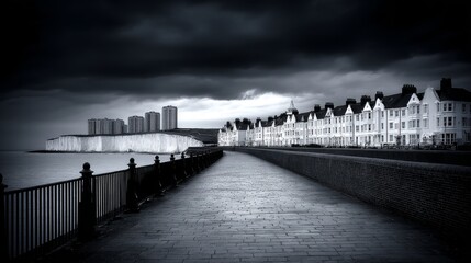 Obraz premium Chalk Cliffs Coastal Path Under Stormy Sky - Dramatic coastal scene, power of nature, serene pathway, contrast of buildings and cliffs, ominous clouds