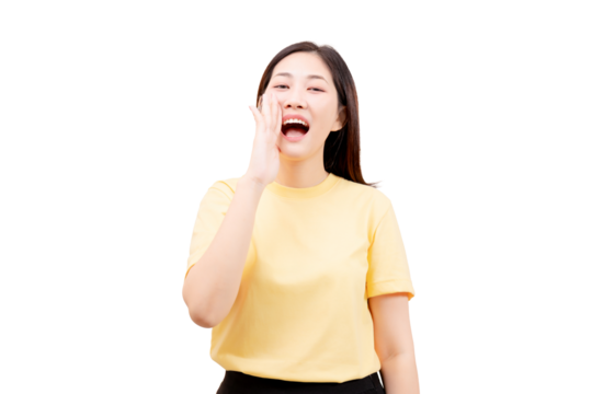 Asian young beautiful woman in a yellow shirt calling out with her hand near her mouth.