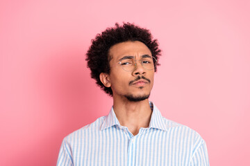 Fototapeta premium Young confident man with curly hair wearing casual attire, standing against a pink background