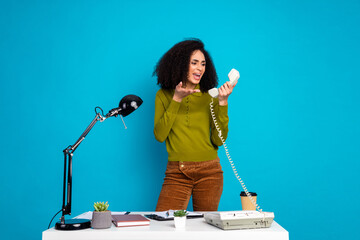 Young woman in stylish outfit holding retro telephone handset while gesturing enthusiastically at...