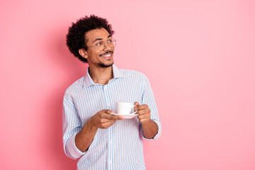 Stylish young man with glasses holding a coffee cup against a pink backdrop, showcasing elegance...