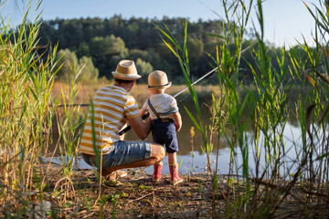 Father and young son fishing together on a lakeshore