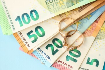European union Euro money bills and coins with wedding rings on blue table