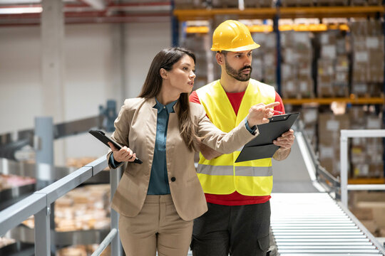 The manager explains safety procedures to a safety officer in the warehouse, emphasizing the importance of proper protocols.