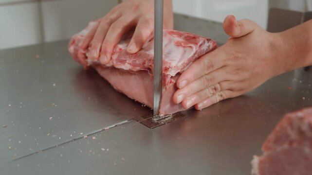 Imagem 4k de uma costela su&iacute;na sendo cortada em uma bancada de serra de fita por um a&ccedil;ougueiro