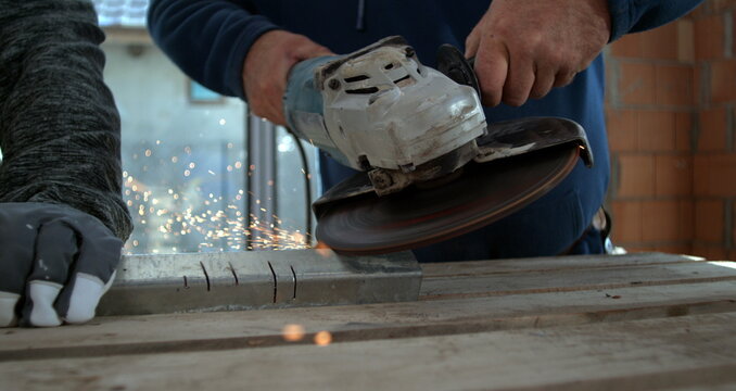 Closeup of worker using angle grinder on metal, sparks illuminating hands, focus on precision and teamwork in construction setting, 800 fps slow motion