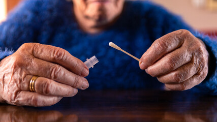 Old woman holding a cotton swab for nose to collect a possible positive COVID-19