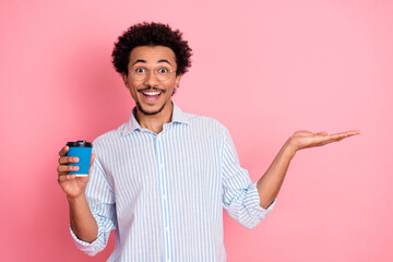Happy young man with coffee cup gesturing on pink background, showcasing style and casual elegance
