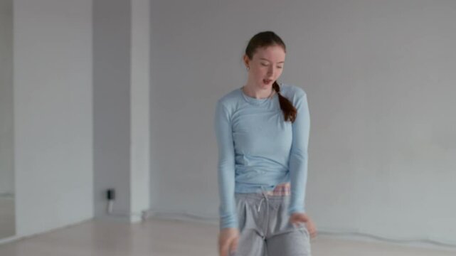 Zoom in copy space shot of young Caucasian girls practicing modern dance moves in turns in minimalist studio