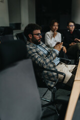 Business people collaborating late at night in an office setting. The image shows team members working together using digital devices, highlighting a dedicated and dynamic work environment.