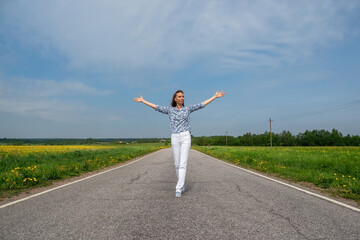 Happy woman running on country road in summer