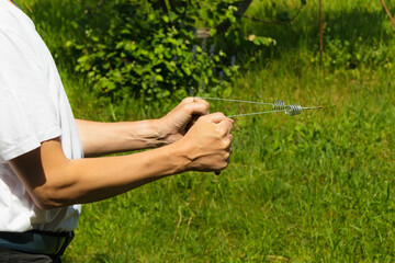 Two L-shaped metal wire rods, called dowsing or divining rods in the hands of a dowser. Modern...