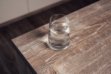 A glass of water sits on a wooden table