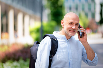 Confident man walking on the city street and using his phone
