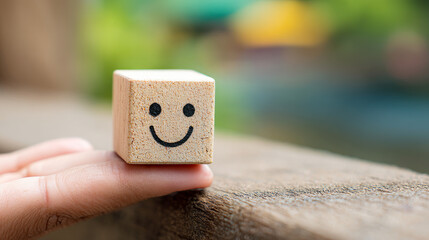 A happy face in a hand symbolizes positive thinking. A smiling wooden cube represents mental health awareness on World Mental Health Day.