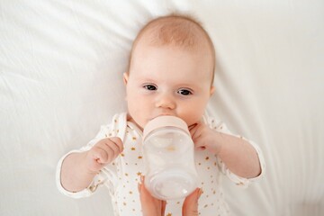 Mom's hand holds a bottle of milk for a newborn baby. Small child with bottle close-up, High quality 4k footage
